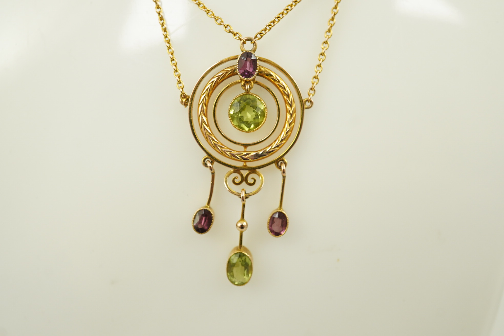 An Edwardian 9ct gold, peridot and garnet set drop pendant necklace, by Murrle Bennett & Co